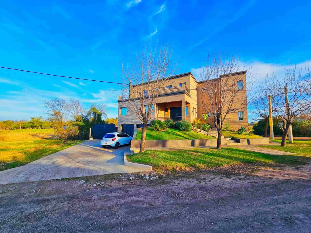Vista frontal de la casa de lujo de tres plantas con jardín y entrada para coches