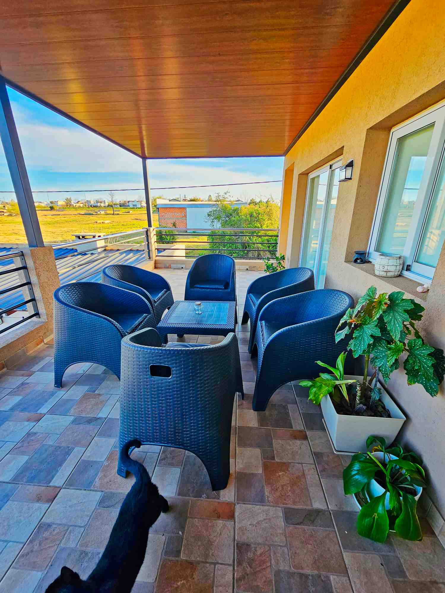 Terraza de vivienda de lujo con sillas de mimbre y mesa, con vistas al paisaje