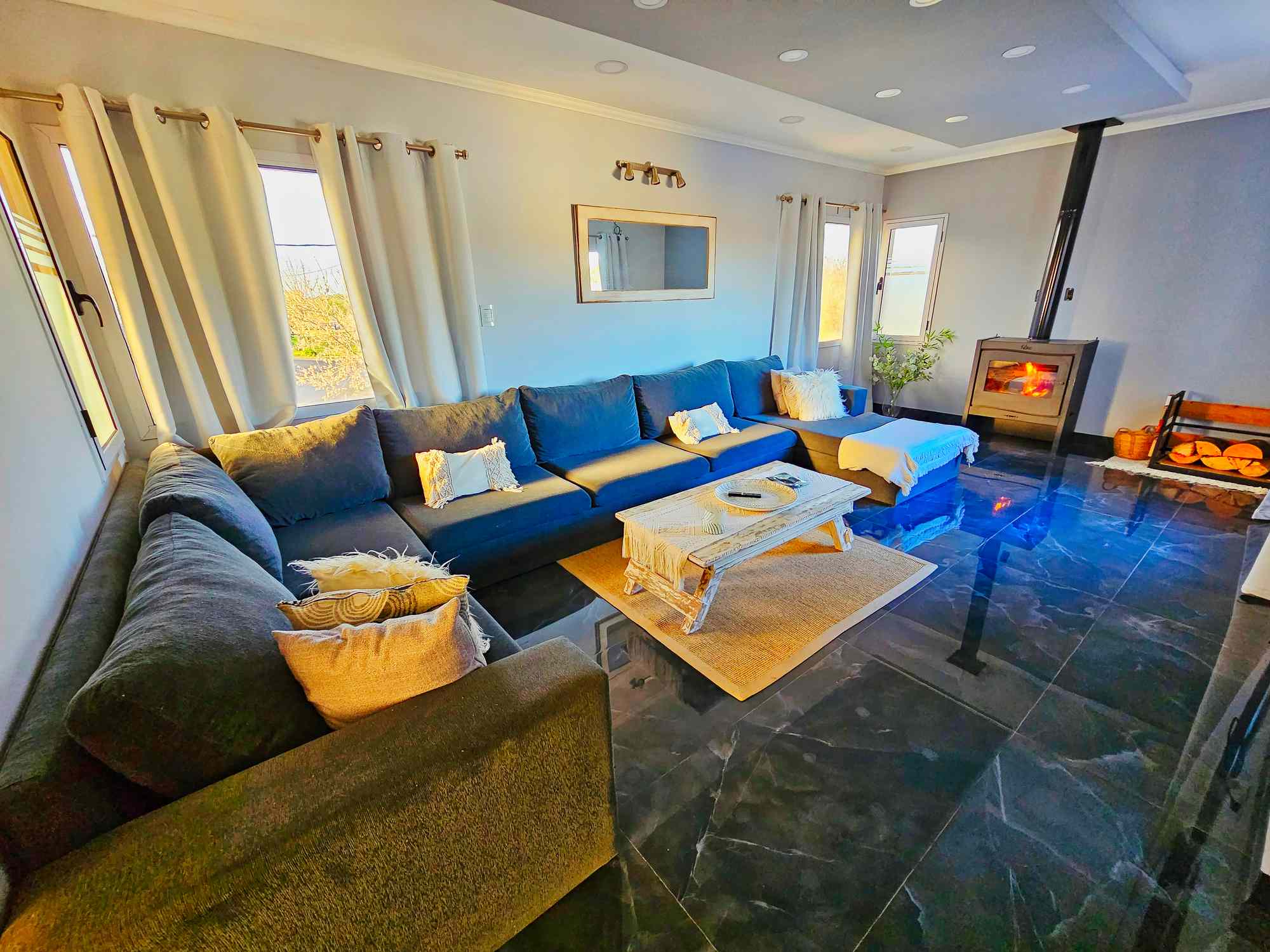 Sala de estar con sofá azul, chimenea y suelo de mármol en vivienda de lujo