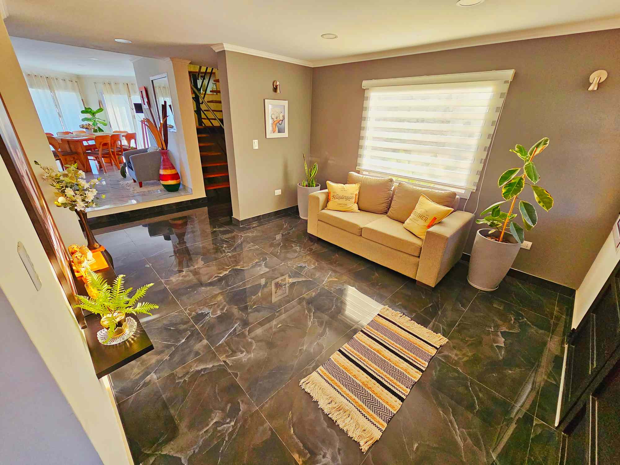 Sala de estar de la casa de lujo con sofá beige, piso de mármol negro y plantas decorativas